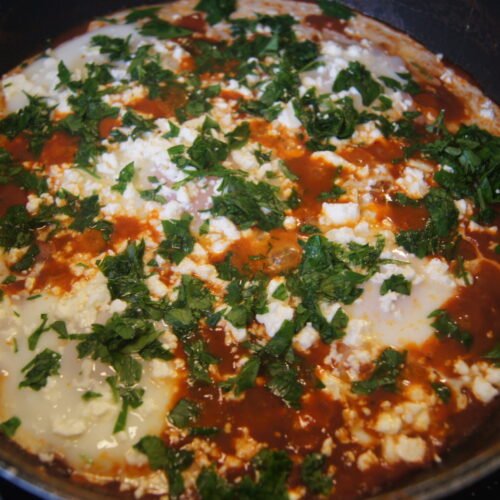 Shakshuka with poached eggs in a spiced tomato sauce topped with feta