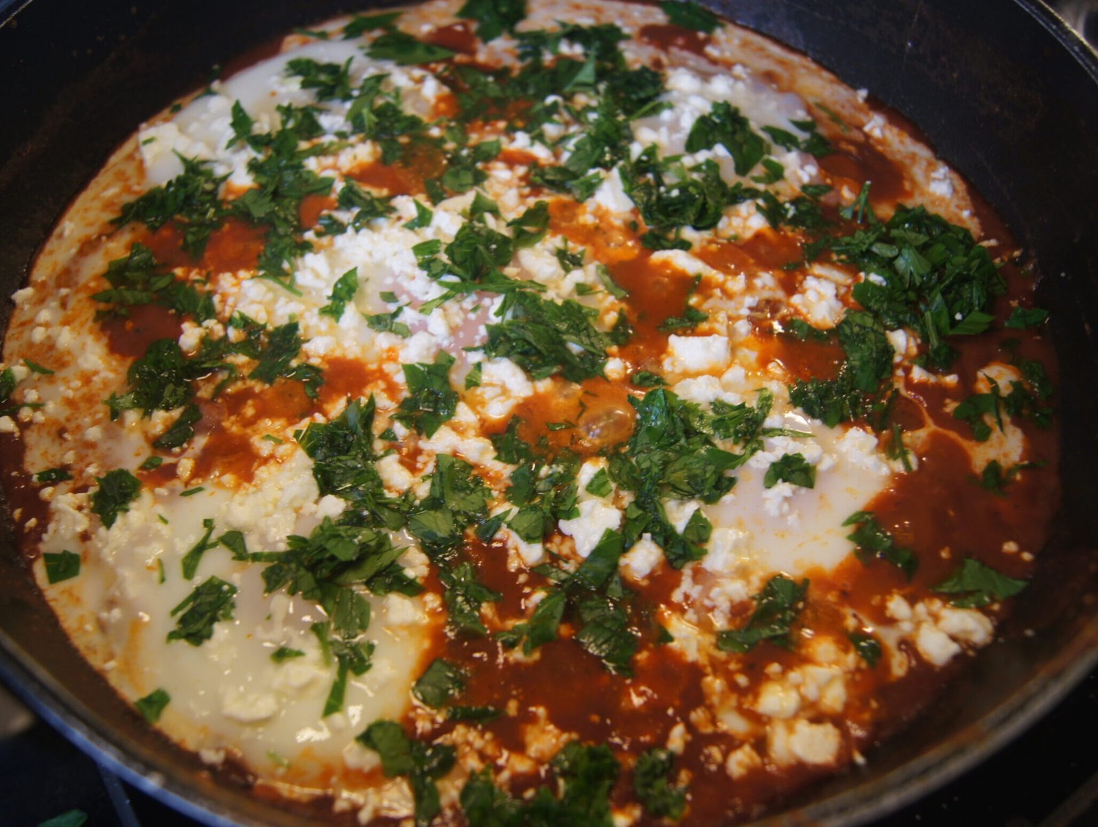 Shakshuka with poached eggs in a spiced tomato sauce topped with feta