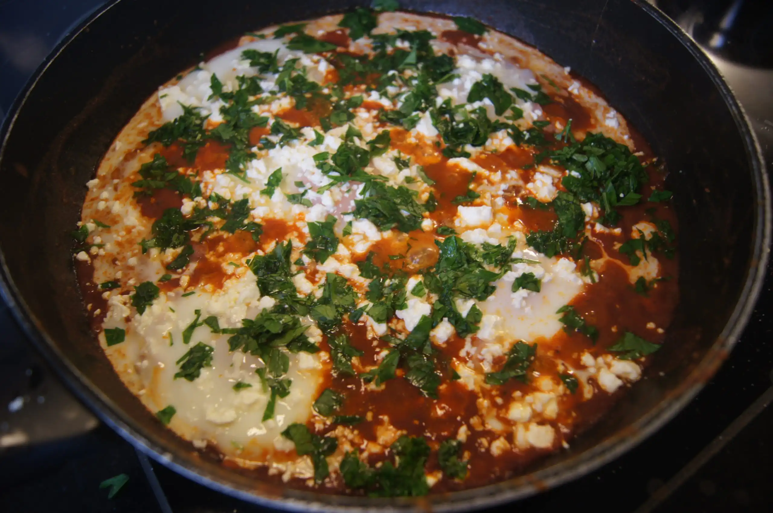 Shakshuka with poached eggs in a spiced tomato sauce topped with feta