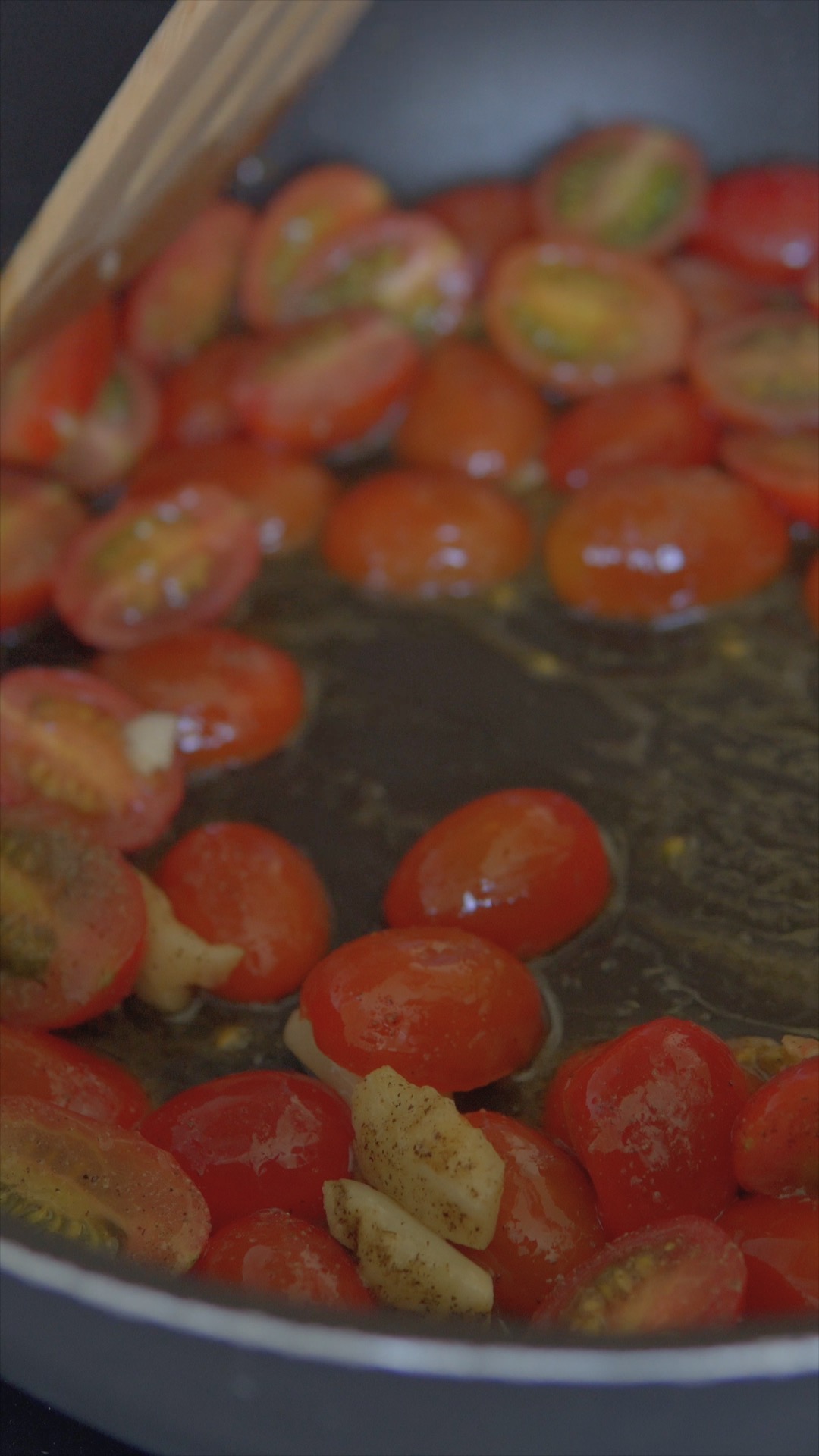 Cherry tomatoes and garlic sizzling in a frying pan