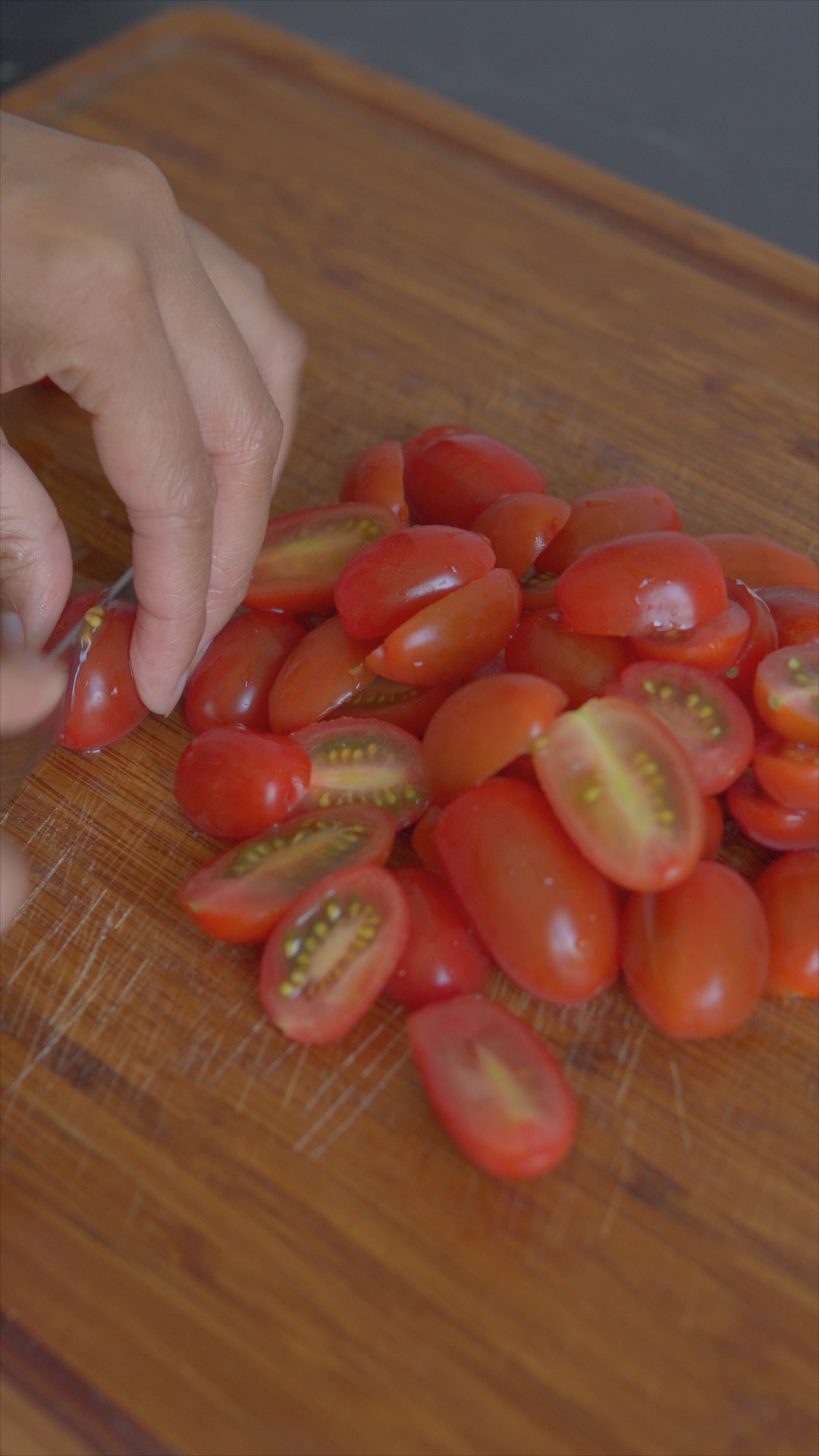 Halved cherry tomatoes on a wooden chopping board