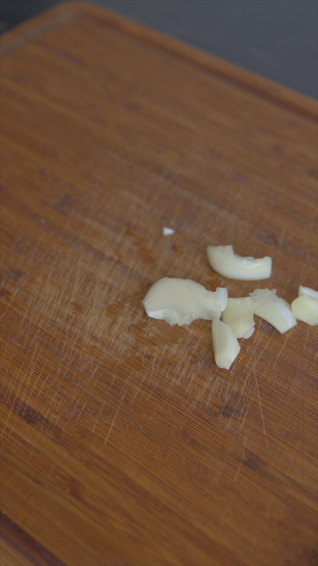 Crushed garlic cloves on a wooden chopping board