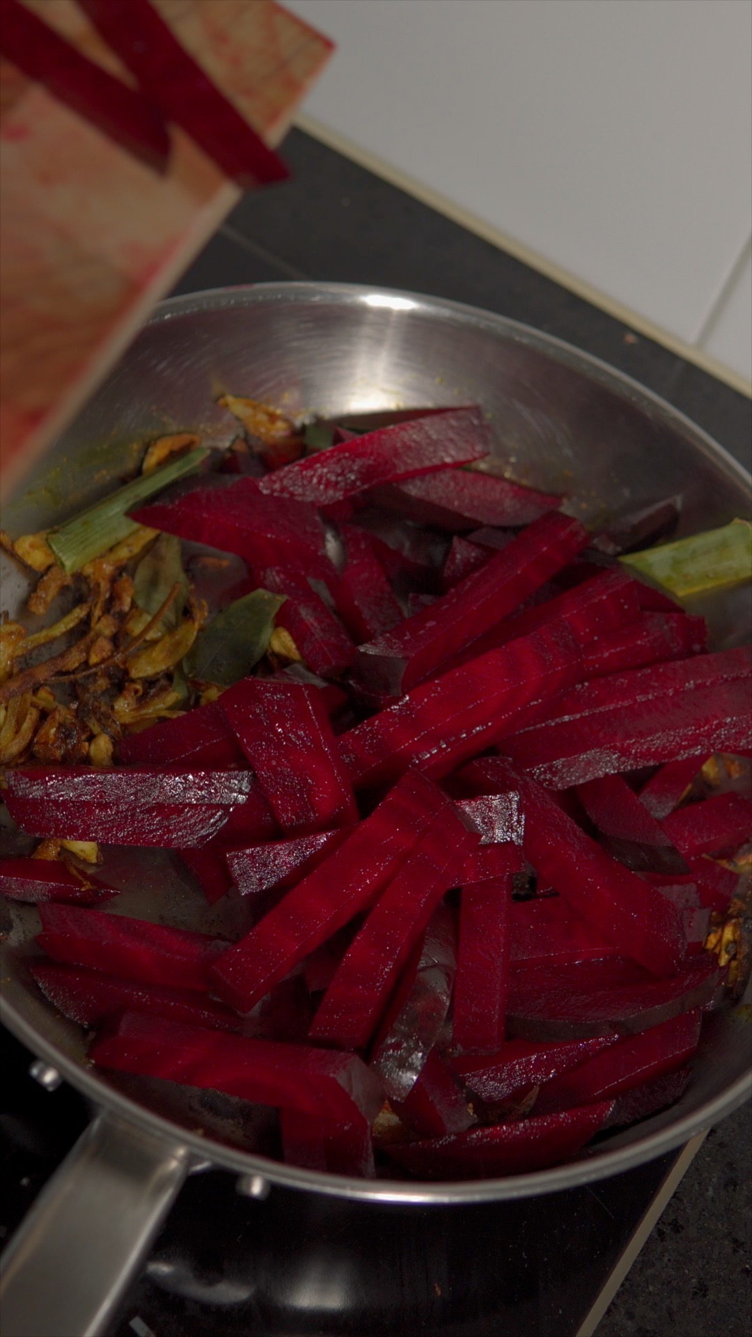 Adding beetroot strips to the pan with spices, curry leaves and pandan